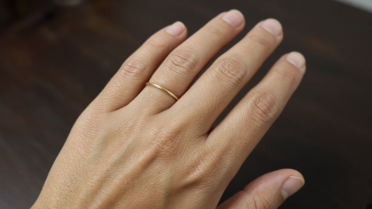 A hand wearing a thin gold smart ring
